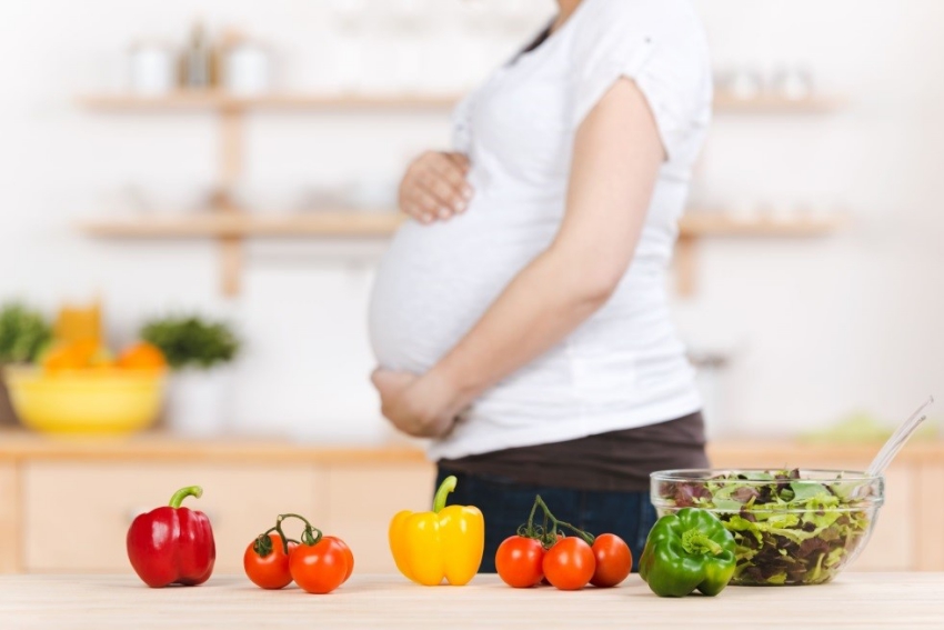 une femme enceinte qui cuisine des légumes